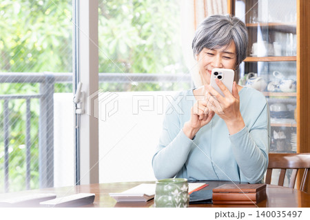 自宅でスマホを操作するシニア女性 自宅でスマホを操作するシニア女性 140035497