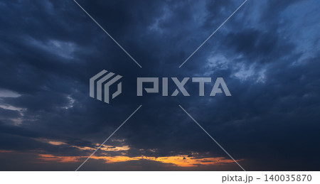 Dramatic dark storm clouds gather above an orange sunset Dramatic dark storm clouds gather above an orange sunset 140035870