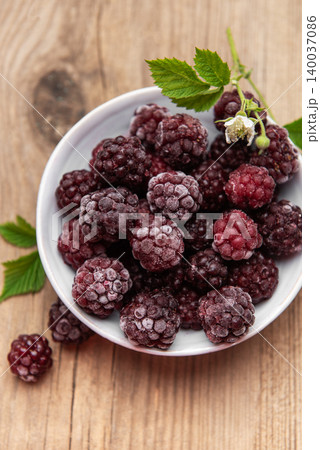 Frozen blackberries on wooden table in white bowl Frozen blackberries on wooden table in white bowl 140037086