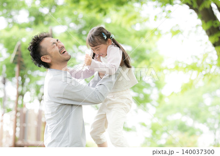 新緑の公園で父親と娘が遊ぶ笑顔あふれる家族のふれあいと子育てイメージ 抱っこして高い高い 新緑の公園で父親と娘が遊ぶ笑顔あふれる家族のふれあいと子育てイメージ 抱っこして高い高い 140037300