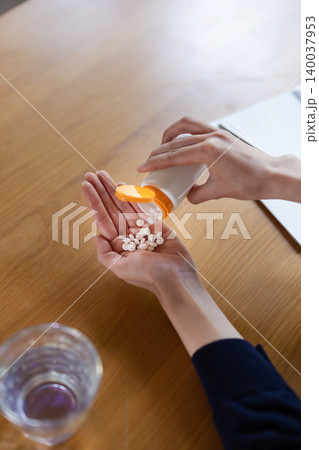 ボトルから錠剤を取り出す女性の手元のクローズアップ 140037953