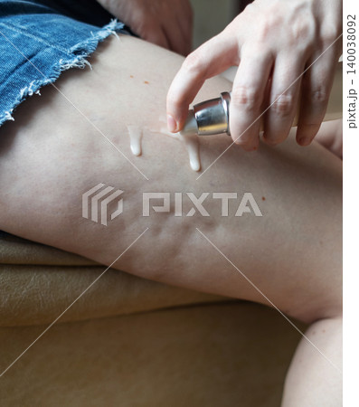 Woman applying anti-cellulite cream from a dispenser bottle onto her thigh skin. Body care routine, weight loss treatment and female lipodystrophy problem concept. Woman applying anti-cellulite cream from a dispenser bottle onto her thigh skin. Body care routine, weight loss treatment and female lipodystrophy problem concept. 140038092