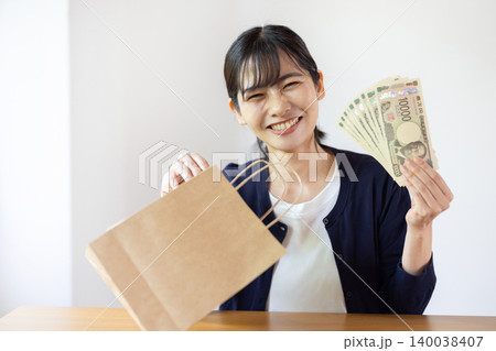 明るい室内で紙袋から1万円札を取り出して笑う日本人の若い女性 明るい室内で紙袋から1万円札を取り出して笑う日本人の若い女性 140038407