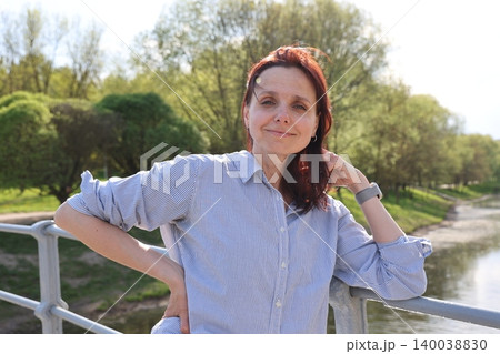 Women's clothing. Fashionable look. A girl in ripped jeans and a light shirt in a park. Women's clothing. Fashionable look. A girl in ripped jeans and a light shirt in a park. 140038830