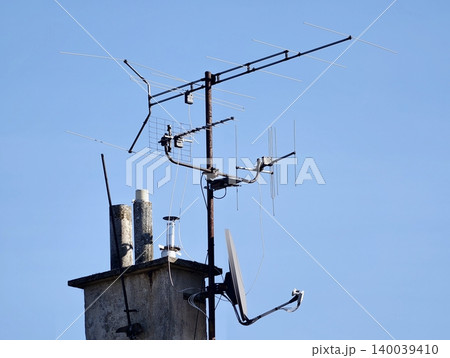 Weathered chimney with rooftop antenna. Broadcast equipment atop aged concrete chimney under clear sky Weathered chimney with rooftop antenna. Broadcast equipment atop aged concrete chimney under clear sky 140039410