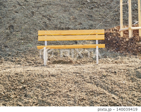 Quiet park bench under bright sunlight. Calm outdoor setting with bright bench and seasonal autumn tones Quiet park bench under bright sunlight. Calm outdoor setting with bright bench and seasonal autumn tones 140039419