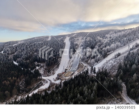 Tranquil alpine resort scene with frosted trees and winding mountain road under overcast sky Tranquil alpine resort scene with frosted trees and winding mountain road under overcast sky 140039505