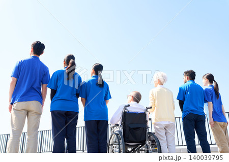 空を見上げる日本人と外国人介護士とシニアの後ろ姿 空を見上げる日本人と外国人介護士とシニアの後ろ姿 140039795