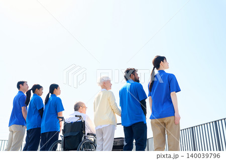 空を見上げる日本人と外国人介護士とシニアの後ろ姿 空を見上げる日本人と外国人介護士とシニアの後ろ姿 140039796