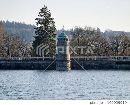 Idyllic setting featuring dam path surrounded by lush forestry and peaceful water reflections Idyllic setting featuring dam path surrounded by lush forestry and peaceful water reflections 140039919
