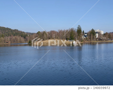 Peaceful island setting featuring secluded dock. Idyllic island scene with tranquil waters and towering tree Peaceful island setting featuring secluded dock. Idyllic island scene with tranquil waters and towering tree 140039972