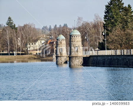 Reflective walk by twin towers. Peaceful public area featuring ornate towers and water reflections Reflective walk by twin towers. Peaceful public area featuring ornate towers and water reflections 140039983