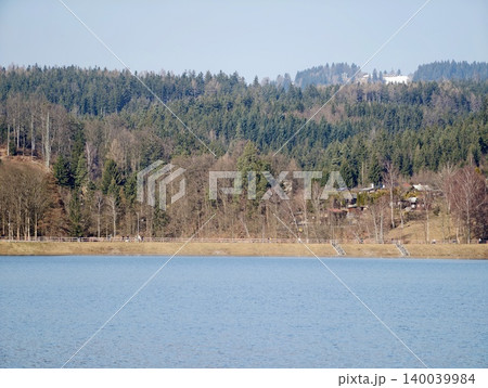 Tranquil blue water reflecting nature. Gentle ripples and distant forest backdrop create harmony Tranquil blue water reflecting nature. Gentle ripples and distant forest backdrop create harmony 140039984