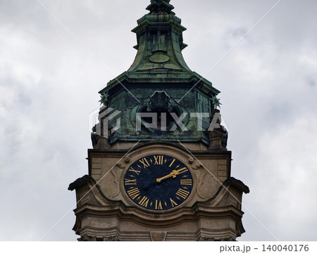 Historic tower under cloudy sky. Architectural monument with baroque elements and weathered finish Historic tower under cloudy sky. Architectural monument with baroque elements and weathered finish 140040176
