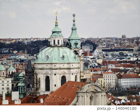 Architectural elements adorn layered city skyline. Sunlit view of ancient bell towers and tiled rooftops 140040180