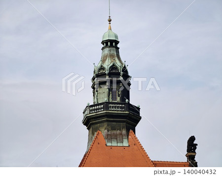 Architectural harmony between fiery red roof tiles and lush patina crowns in urban setting 140040432