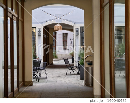 Elegant courtyard with cozy seating. Historic style corridor opens onto peaceful courtyard dining area Elegant courtyard with cozy seating. Historic style corridor opens onto peaceful courtyard dining area 140040483