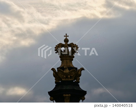Intricate crown sculpture emphasizing baroque artistry with gilded details and atmospheric cloud patterns 140040518