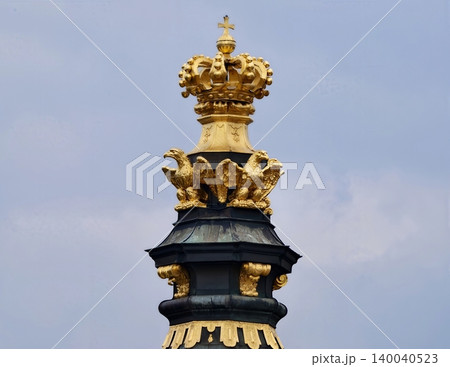 Ornamental tower with detailed crown and radiant gold accents set in historic rooftop scenery 140040523