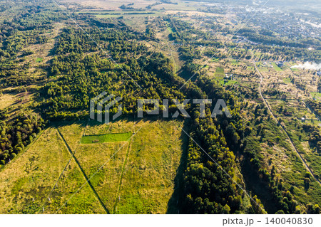 Vast green forests and sun-drenched fields sprawl across this diverse rural landscape, with a winding path cutting through, hinting at remote settlements Vast green forests and sun-drenched fields sprawl across this diverse rural landscape, with a winding path cutting through, hinting at remote settlements 140040830