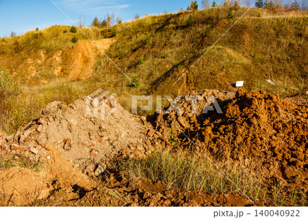 Two distinct piles of earth, one with brick bits, dominate this construction or landfill site. A grassy hill and blue sky form the backdrop Two distinct piles of earth, one with brick bits, dominate this construction or landfill site. A grassy hill and blue sky form the backdrop 140040922