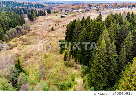 Lush evergreen forest borders a sprawling autumnal valley. Rustic village homes dot the distant hills, painting a serene, rugged natural panorama Lush evergreen forest borders a sprawling autumnal valley. Rustic village homes dot the distant hills, painting a serene, rugged natural panorama 140040933