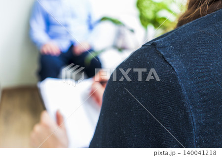 Close Up of Psychologist Hand Taking Notes During Therapy Session with Client 140041218
