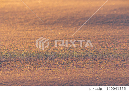 Glistening fresh snow surface textures during golden hour, illuminated by warm sunset light, soft grainy powder, sparkling winter background, crystalline frosty detail, abstract seasonal mood Glistening fresh snow surface textures during golden hour, illuminated by warm sunset light, soft grainy powder, sparkling winter background, crystalline frosty detail, abstract seasonal mood 140041536
