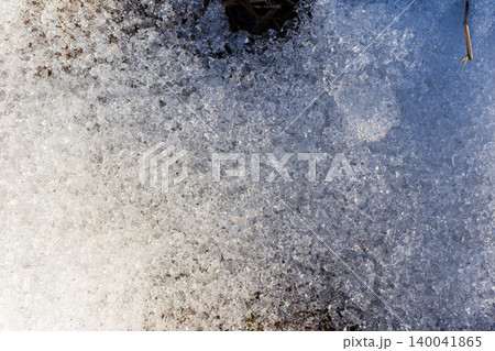 Sun-kissed granular snow melts into glistening icy fragments, revealing nature's awakening. A vibrant, frosty landscape transforming with spring's gentle touch Sun-kissed granular snow melts into glistening icy fragments, revealing nature's awakening. A vibrant, frosty landscape transforming with spring's gentle touch 140041865