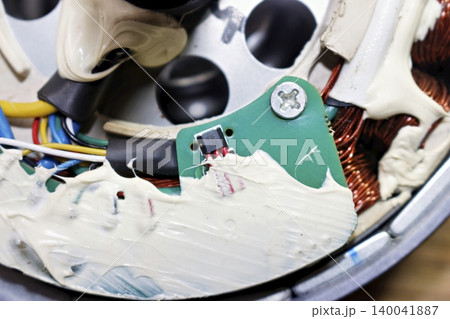 Detailed close-up view of an electric bicycle motor hall effect sensor mounted on a green circuit board inside a disassembled hub motor with white grease and copper windings 140041887