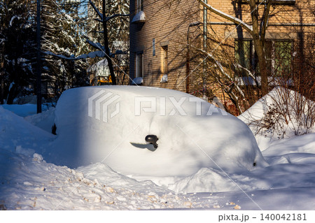 Vehicle cocooned by a massive blanket of fresh snow, only a lone side mirror poking through. Captures the stark beauty and deep freeze of an urban winter morning Vehicle cocooned by a massive blanket of fresh snow, only a lone side mirror poking through. Captures the stark beauty and deep freeze of an urban winter morning 140042181