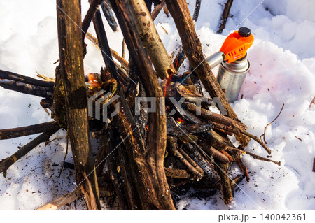 Vibrant orange gas torch quickly ignites kindling for a cozy winter campfire, radiating warmth in snowy wilderness Vibrant orange gas torch quickly ignites kindling for a cozy winter campfire, radiating warmth in snowy wilderness 140042361