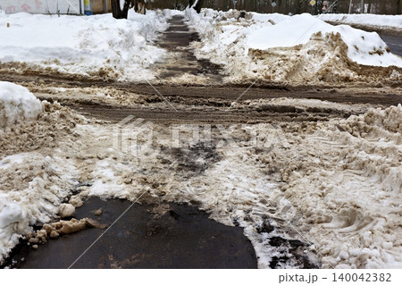 Dirty urban winter sidewalk, partially cleared, with grimy brown snowbanks and slush. Realistic city snow removal aftermath Dirty urban winter sidewalk, partially cleared, with grimy brown snowbanks and slush. Realistic city snow removal aftermath 140042382