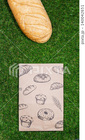 Freshly baked bread and crumpled paper bag on a grass background .Top view. Freshly baked bread and crumpled paper bag on a grass background .Top view. 140042651