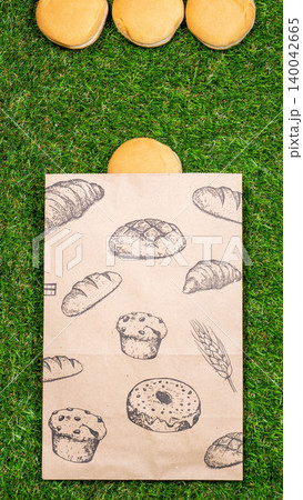 Freshly baked bread and crumpled paper bag on a grass background .Top view. Freshly baked bread and crumpled paper bag on a grass background .Top view. 140042665