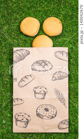 Freshly baked bread and crumpled paper bag on a grass background .Top view. Freshly baked bread and crumpled paper bag on a grass background .Top view. 140042670