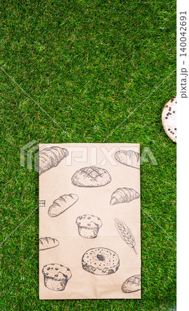 Freshly baked donuts and crumpled paper bag on a grass background .Top view. 140042691