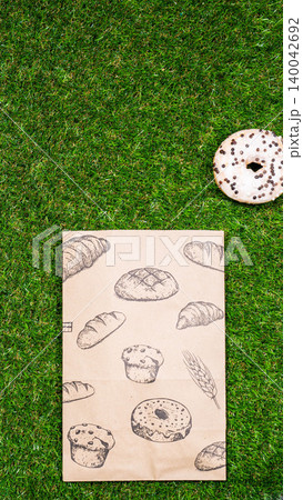 Freshly baked donuts and crumpled paper bag on a grass background .Top view. 140042692