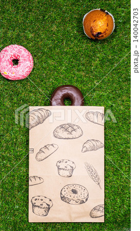 Freshly baked donuts and crumpled paper bag on a grass background .Top view. Freshly baked donuts and crumpled paper bag on a grass background .Top view. 140042703