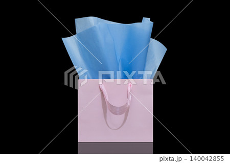 Craft paper gift bag with tissue paper isolated on a black background Craft paper gift bag with tissue paper isolated on a black background 140042855