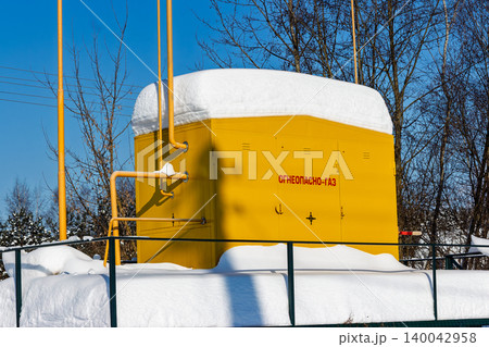 Yellow gas substation with FLAMMABLE GAS warning in a snowy Russian rural landscape under a crisp blue winter sky. Energy infrastructure theme, Russia 140042958