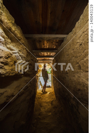 Young woman standing in narrow cave passage inside Aladzha Monastery Bulgaria 140043119