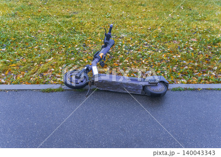 Wet pavement with abandoned scooter. Rainy sidewalk scene featuring discarded scooter and puddles nearby Wet pavement with abandoned scooter. Rainy sidewalk scene featuring discarded scooter and puddles nearby 140043343