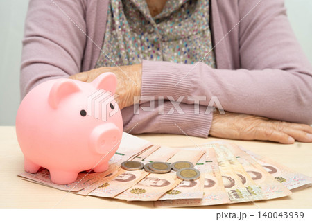 Retired elderly woman counting coins money with piggy bank and worry about monthly expenses and treatment fee payment. Retired elderly woman counting coins money with piggy bank and worry about monthly expenses and treatment fee payment. 140043939
