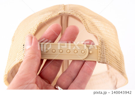 Adjustable beige trucker hat with plastic snapback closure, mesh back mockup in hand closeup 140043942