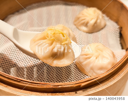 蒸篭料理。蒸篭で蒸して作る台湾料理の小籠包。生姜を乗せた小籠包をスプーンで持ち上げる様子。 140043958