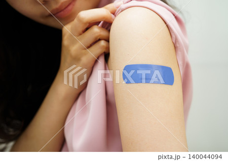 HPV, Human papillomavirus, Asian young woman receiving vaccine with blue bandage. 140044094