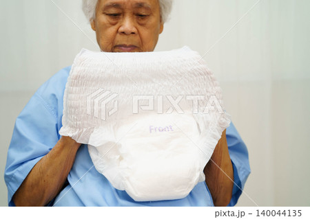 Asian senior woman patient wearing adult incontinence diaper pad in hospital. 140044135