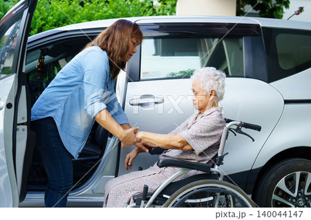 Caregiver help Asian elderly woman disability patient use wheelchair to get in car. Caregiver help Asian elderly woman disability patient use wheelchair to get in car. 140044147
