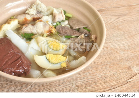 large rice noodles chop and crispy pork couple organ topping egg in clear blood soup on bowl large rice noodles chop and crispy pork couple organ topping egg in clear blood soup on bowl 140044514